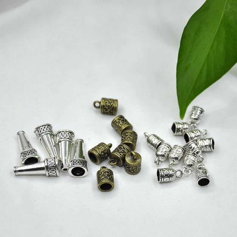 May include: Assortment of silver and bronze metal end caps for jewelry making. The end caps have an ornate design and are perfect for adding a touch of elegance to your projects.