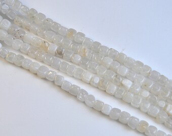 Peut inclure: Un brin de perles carrées de couleur blanche. Les perles sont opaques et ont un aspect légèrement nuageux.