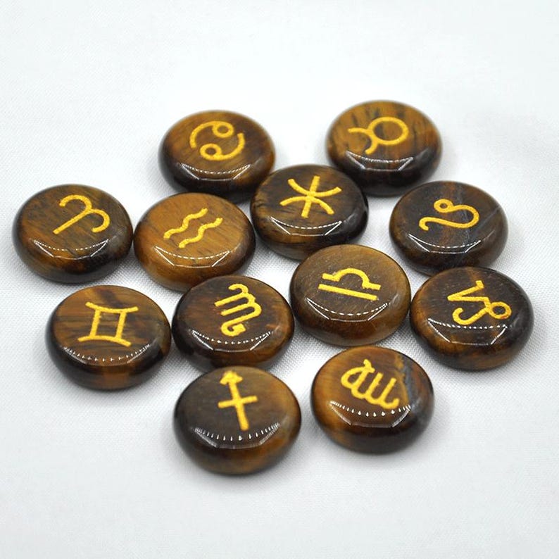 May include: Twelve tiger's eye stones, each with a different zodiac symbol engraved in gold. The stones are brown and gold and have a smooth, polished finish.