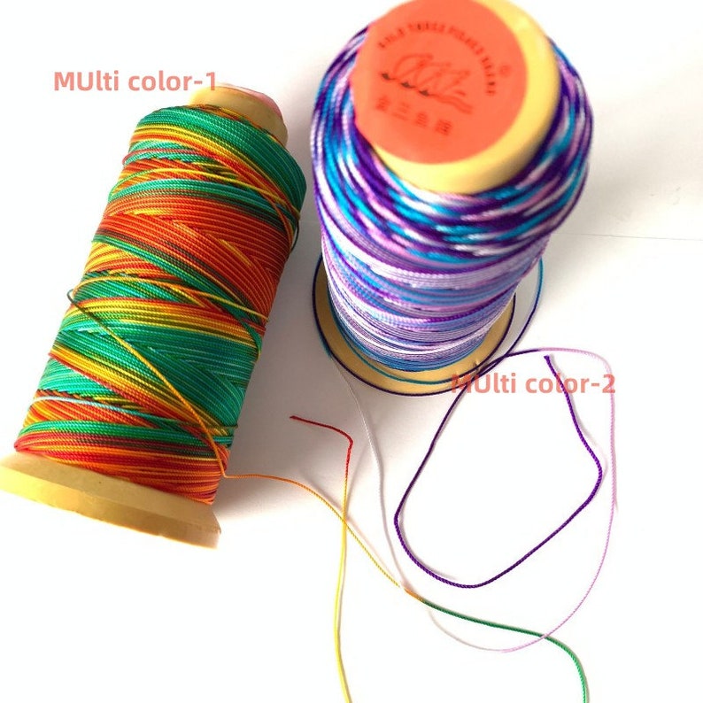 May include: Two spools of colorful thread. One spool is wrapped with orange, yellow, green, and red thread. The other spool is wrapped with blue, purple, and white thread. The text "Multi color-1" and "Multi color-2" are visible.