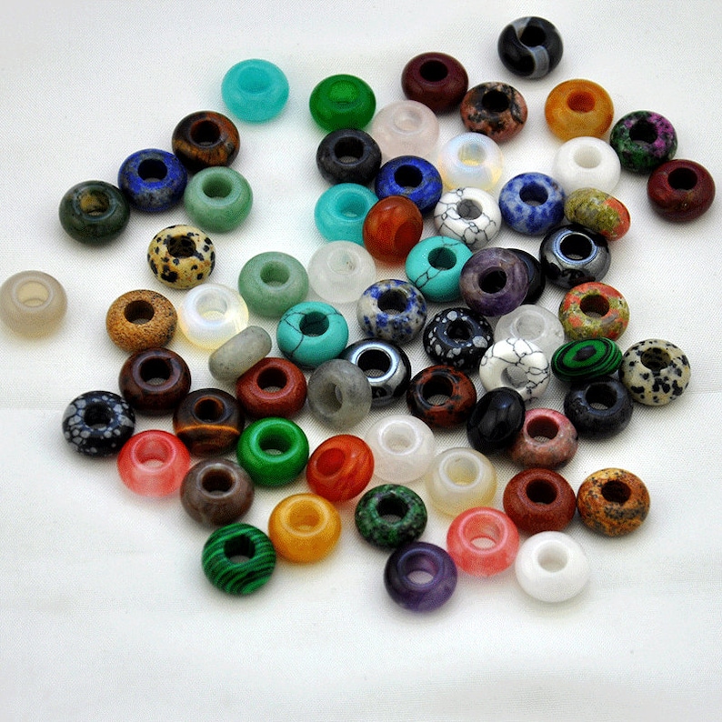 May include: A collection of colorful gemstone beads with holes for stringing. The beads are made of various materials, including agate, turquoise, jasper, and amethyst.