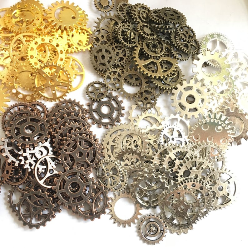 Puede incluir: Una colecci&oacute;n de engranajes de metal dorado y plateado de varios tama&ntilde;os. Los engranajes est&aacute;n dispuestos en un patr&oacute;n aleatorio y algunos se superponen.