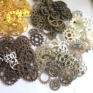 Puede incluir: Una colecci&oacute;n de engranajes de metal dorado, plateado y bronce de varios tama&ntilde;os. Los engranajes est&aacute;n dispuestos en un patr&oacute;n aleatorio sobre un fondo blanco.