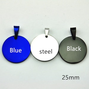 Puede incluir: Tres colgantes redondos de metal, de 25 mm de diámetro, con un bucle en la parte superior. Los colgantes son azules, plateados y negros. Las palabras "Azul", "acero" y "Negro" están impresas en los colgantes.