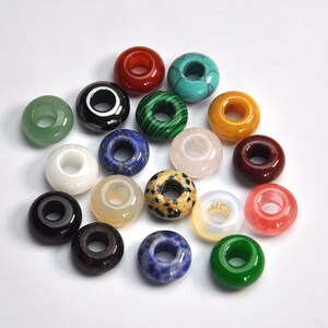 May include: Assortment of 16 gemstone donut beads with various colors and patterns. The beads are made of natural stones and have a hole in the center for stringing.