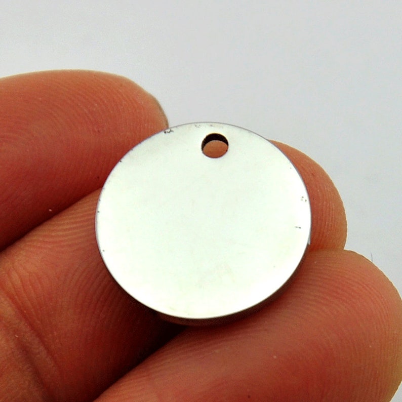 May include: A silver round metal tag with a hole in the center. The tag is blank and ready to be engraved.