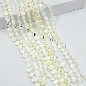 Peut inclure: Neuf brins de perles de coquillage blanches de différentes formes, notamment des carrés, des étoiles, des cœurs et des cercles. Les perles sont enfilées sur un cordon blanc.