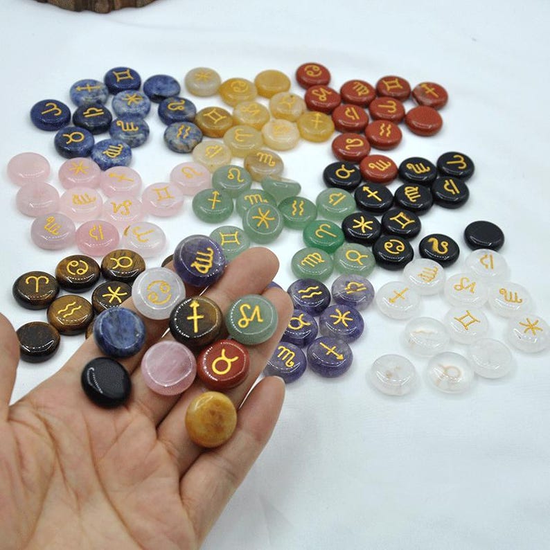 May include: A collection of 12 zodiac sign stones, each with a different color and symbol. The stones are arranged in a circle, with the signs of the zodiac in order. The stones are made of various materials, including amethyst, agate, and jasper.