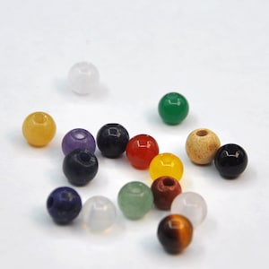 May include: Assortment of round gemstone beads in various colors, including white, yellow, purple, blue, red, green, brown, and black.