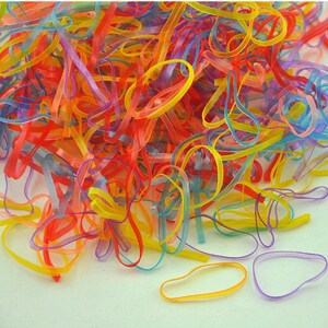 Pu&ograve; includere: Un grande mucchio di elastici per capelli in gomma di vari colori, dal rosso all'arancione, dal giallo al verde, dal blu al viola.