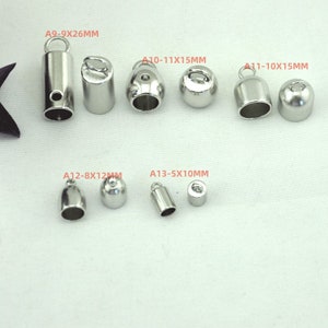 May include: Assortment of silver metal end caps for cords or jewelry making. The caps are in various sizes and shapes, including round, cylindrical, and bell-shaped. The sizes are labeled with the text A9-9X26MM, A10-11X15MM, A11-10X15MM, A12-8X12MM, and A13-5X10MM.