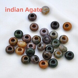 May include: A collection of 25 assorted Indian agate beads. The beads are round with a hole in the center and are various shades of brown, green, and white.