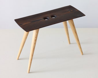 Tabouret en bois avec poignées perforées, Banc unique avec siège finition brûlée, Cadeau unique fait main, fabriqué en Lettonie par Didzis Jurkovskis.