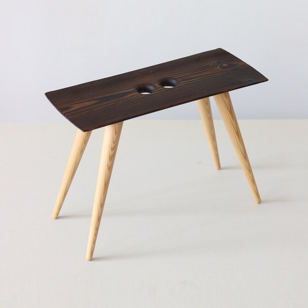 Tabouret en bois avec poignées perforées, Banc unique avec siège finition brûlée, Cadeau unique fait main, fabriqué en Lettonie par Didzis Jurkovskis.