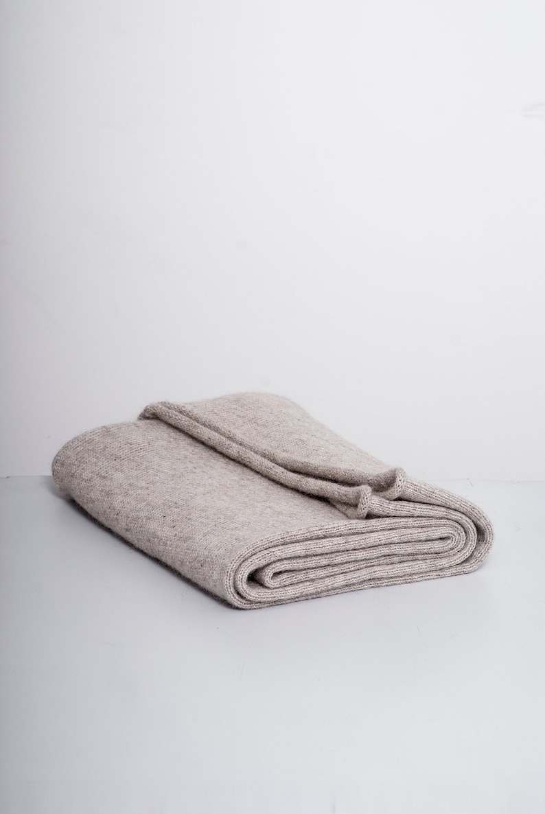May include: A folded beige knitted throw blanket.