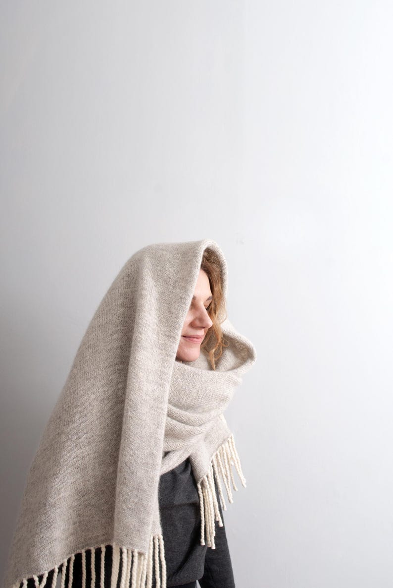 Profile of a smiling woman wearing a cozy beige melange mohair wool blanket scarf wrapped around her head.