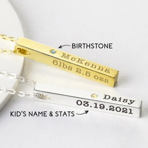 May include: Two gold and silver bar necklaces with birthstones. The gold necklace has the name McKenna, 6 lbs 2.5 ozs, and a blue birthstone. The silver necklace has the name Daisy, 03.19.2021, and a clear birthstone.
