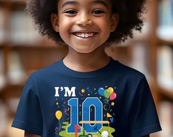 May include: Navy blue t-shirt with a colourful graphic design. The design includes the text "I'M 10 Let's PAR-TEE" with a golf cart, golf ball, and balloons. The shirt is for a child's tenth birthday.