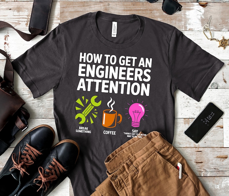 Dark t-shirt with "How to Get an Engineer's Attention" text and icons.
