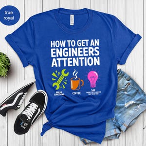 Royal blue t-shirt with "How to Get an Engineer's Attention" text and icons.