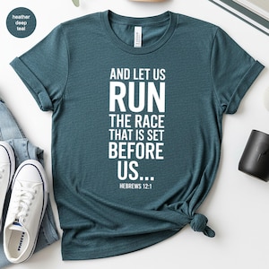 Puede incluir: Camiseta de color verde azulado oscuro con el texto blanco "AND LET US RUN THE RACE THAT IS SET BEFORE US... Hebrews 12:1". La camiseta está anudada en la parte inferior. Zapatillas blancas y vaqueros azules son visibles.