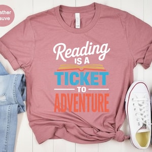 Heather mauve t-shirt with "Reading is a ticket to adventure" text.
