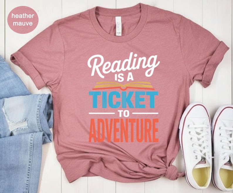 Heather mauve t-shirt with "Reading is a ticket to adventure" text.