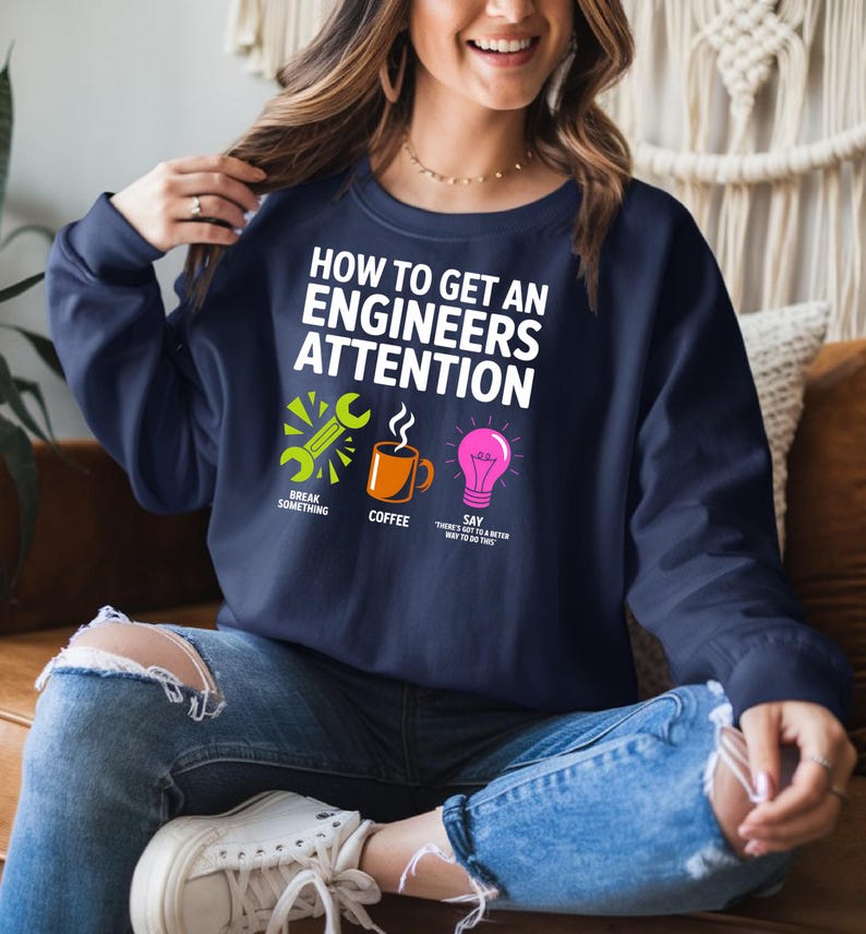 Navy sweatshirt with "How to Get an Engineer's Attention" and three icons.