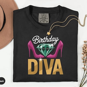 May include: Black t-shirt with the words "Birthday Diva" in white and gold lettering. The design includes a green diamond, pink high heels, and a gold star necklace. The shirt is a Comfort Colors XL-TG-EG.