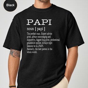 May include: Black t-shirt with the word "PAPI" in large white letters. Below the word "PAPI" is a definition that describes the perfect man. The t-shirt is made of a soft material.