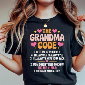May include: Black t-shirt with the text "THE GRANDMA CODE" in pink, orange, and yellow. The text includes phrases like "Hugs are mandatory" and "Bedtime is whenever". A fun gift for grandmothers.