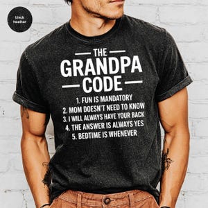 May include: Black heather t-shirt with the text "THE GRANDPA CODE" in white. The shirt lists five rules, including "FUN IS MANDATORY" and "BEDTIME IS WHENEVER". The shirt is a casual wear item.