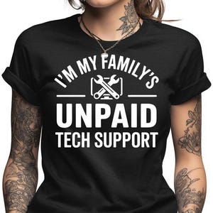 May include: Black t-shirt with white text that reads "I'M MY FAMILY'S UNPAID TECH SUPPORT". The design includes a graphic of crossed wrenches. The shirt has rolled-up sleeves.