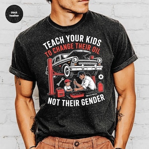 May include: Black heather t-shirt with a graphic featuring a classic car on a lift, a mechanic, and a child. The text reads "Teach your kids to change their oil, not their gender."