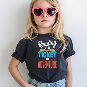 Girl wearing t-shirt with "Reading is a ticket to adventure" text.