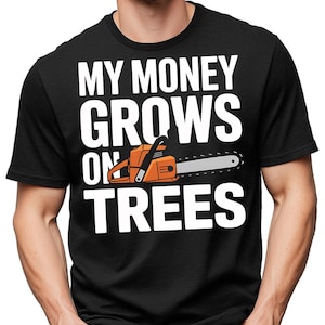 May include: Black t-shirt with the text "MY MONEY GROWS ON TREES" in white block letters. An orange and gray chainsaw graphic is featured in the design. The shirt is a crew neck style.