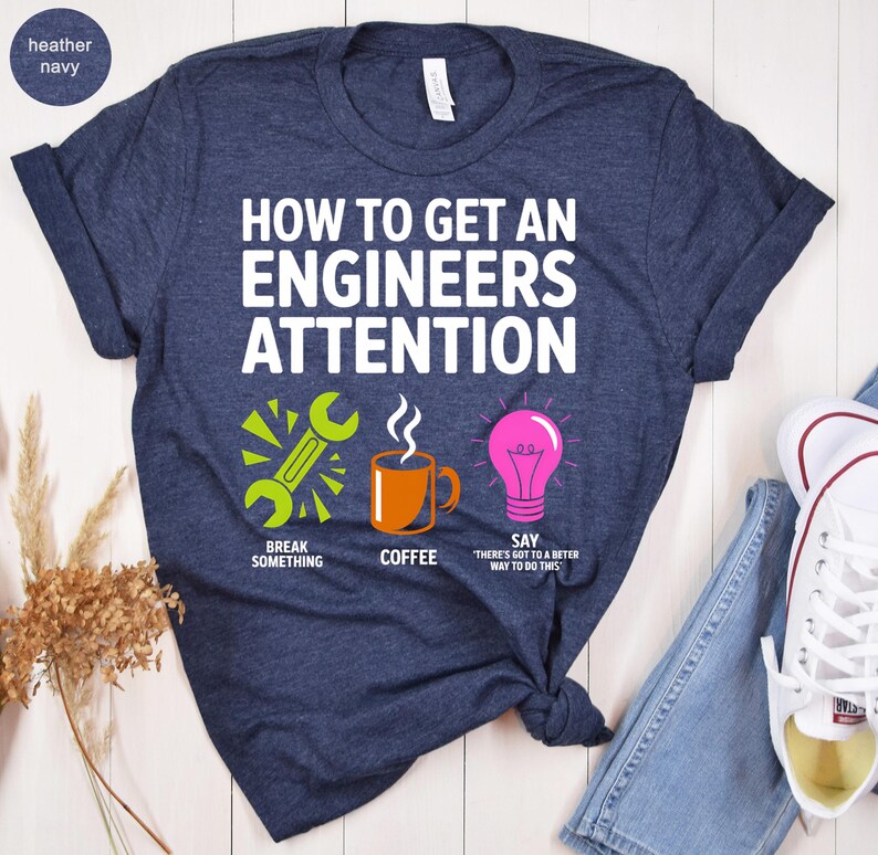 T-shirt with text "How to get an engineer's attention" and icons for breaking, coffee, and a lightbulb.