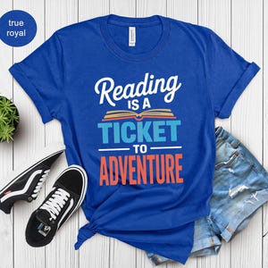 Blue t-shirt with "Reading is a ticket to adventure" graphic.