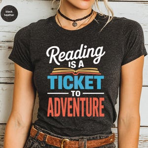Dark heather t-shirt with "Reading is a ticket to adventure" text design.