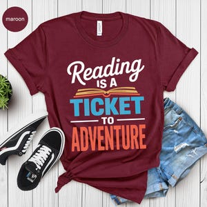 Maroon t-shirt with "Reading is a ticket to adventure" text.
