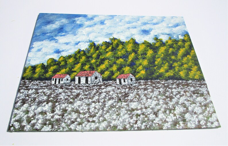 May include: A painting of a rural landscape with three white houses with red roofs in a field of white cotton. The houses are in front of a line of green trees with yellow accents. The sky is blue with white clouds.