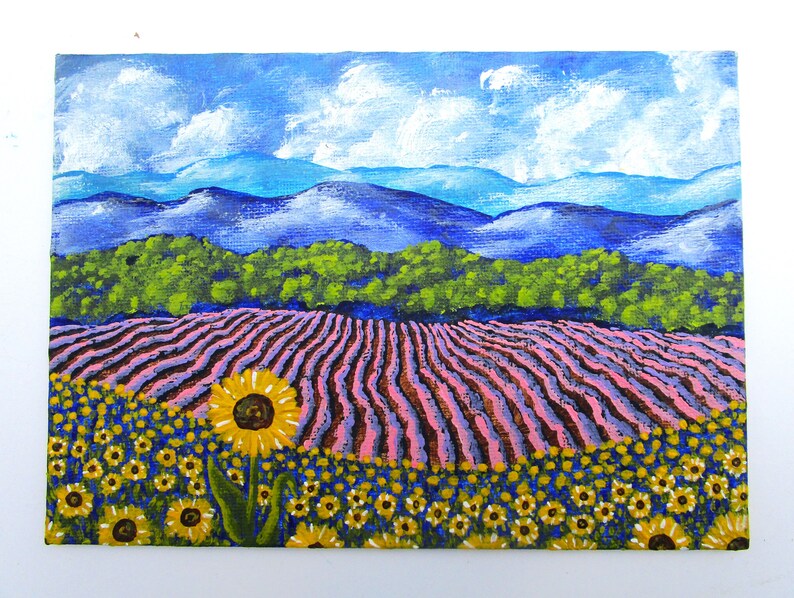 May include: A painting of a field of sunflowers in the foreground with a field of lavender in the middle ground and a mountain range in the background. The sky is blue with white clouds.