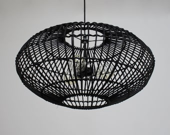 Könnte beinhalten: Schwarze geflochtene Pendelleuchte mit rundem, käfigartigem Design. Die Leuchte hat ein schwarzes Kabel und hängt von der Decke.