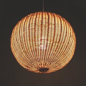 May include: A round, woven pendant light fixture with a warm, golden glow.