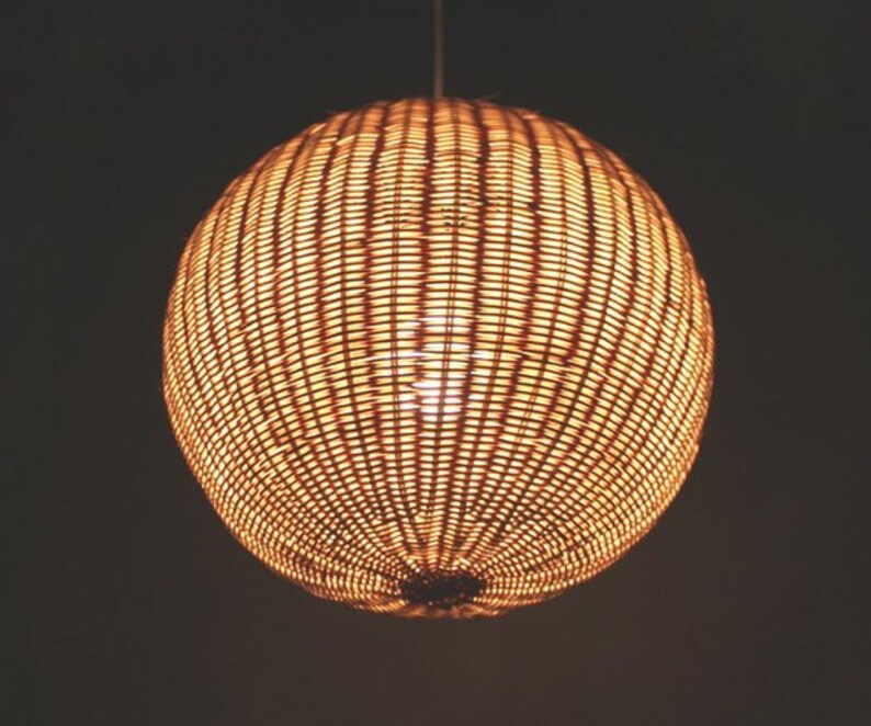 May include: A round, woven pendant light fixture with a warm, golden glow.