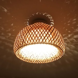 Puede incluir: Una lámpara de techo de bambú tejido con un brillo amarillo cálido.