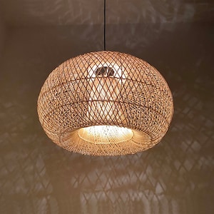 May include: A round, woven, light brown pendant lamp with a white light shining through the woven pattern.