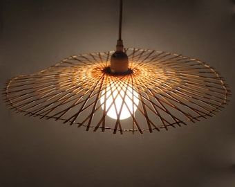 May include: A woven bamboo pendant light fixture with a round, flat shade and a white light bulb.