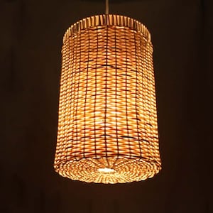 Può includere: Un lampadario a sospensione in vimini intrecciato con una calda luce gialla.