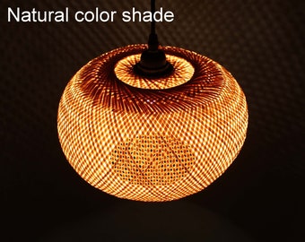 May include: A natural-colored, round, woven bamboo pendant light fixture. The light fixture is hanging from a black cord and is illuminated with a warm, yellow light.